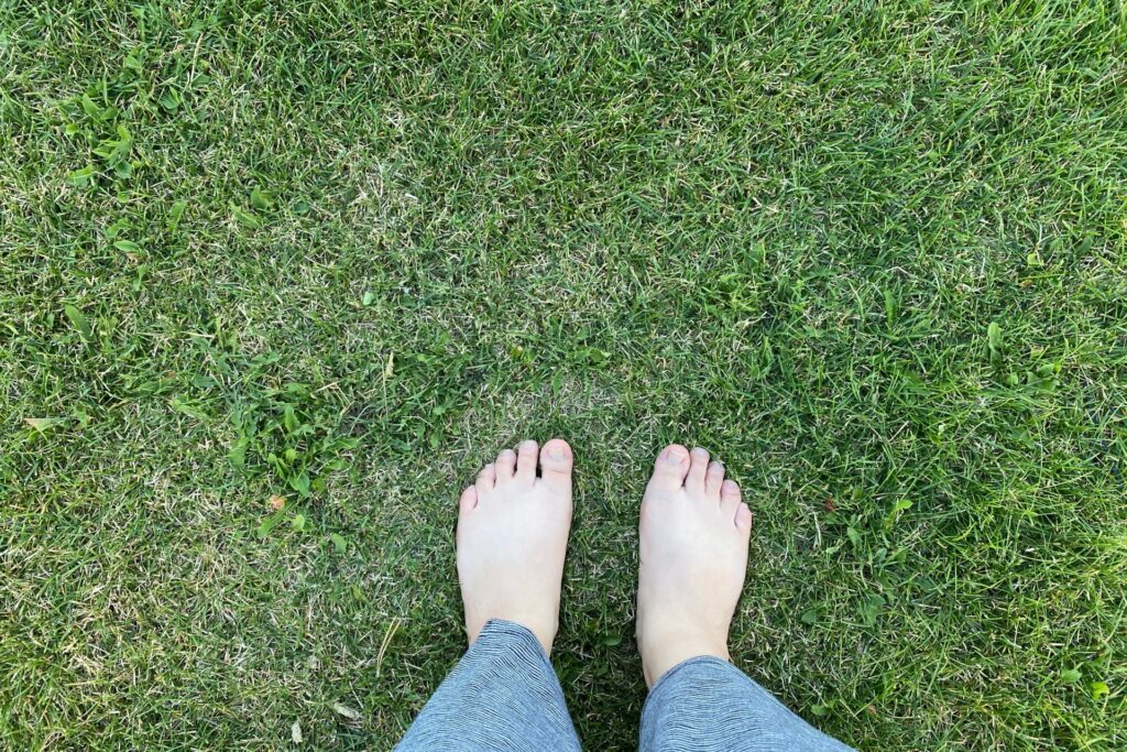 グラウンディング アーシング 裸足で芝生を歩く女性